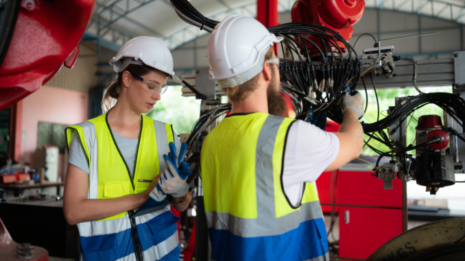 Mitarbeiter reparieren eine Maschine (über WOSUNA / Shutterstock.com)